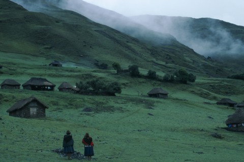 PERU, Ayacucho Province, Choquetira , Village of thatched homes on green hillside with mist seen