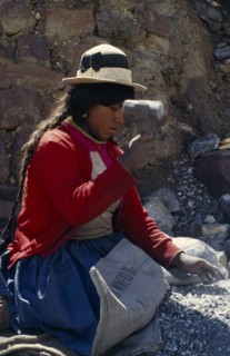 BOLIVIA, Chukiuta, Woman knelling on a Banco Minero de Bolivia sack breaking rocks into small