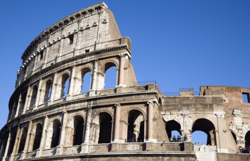 ITALY, Lazio, Rome, Detail of The Colosseum amphitheatre exterior with tourists walking past built