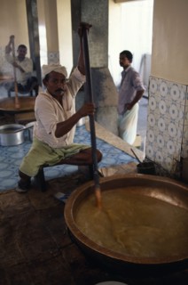 OMAN, Muscat, "Men stirring large, shallow dish of halva."
