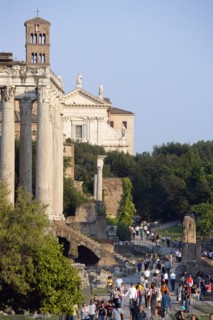 ITALY, Lazio, Rome, Tourists walking past the Temple of Antoninus and Faustina in the Forum with