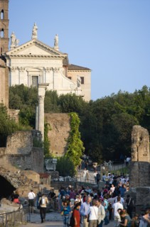 ITALY, Lazio, Rome, Tourists walking past the Temple of Antoninus and Faustina in the Forum with