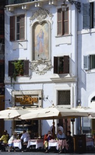 ITALY, Lazio, Rome, People seated outside a restaurant at tables in the shade of umbrellas below a