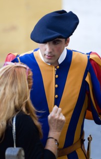 ITALY, Lazio, Rome, Vatican City A Swiss Guard in full ceremonial uniform dress talking to a female