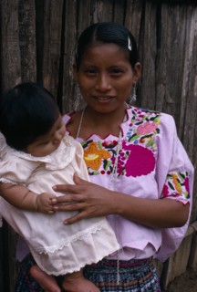 GUATEMALA, Alta Verapaz, Sacaak , Q’eqchi Indian mother wearing a traditional embroidered blouse