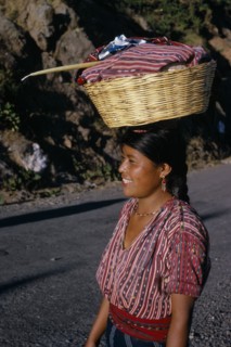 GUATEMALA, Lake Atitlan, Indian girl walking along road carrying a basket of washing on top of her
