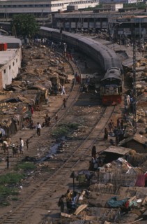 BANGLADESH, Dhaka, Train travelling through Tejgoan slum with ramshackle dwellings beside tracks