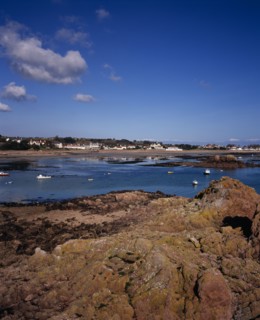 UNITED KINGDOM, Channel Islands, Jersey, Grouville. View across rocky foreshore with small boats on
