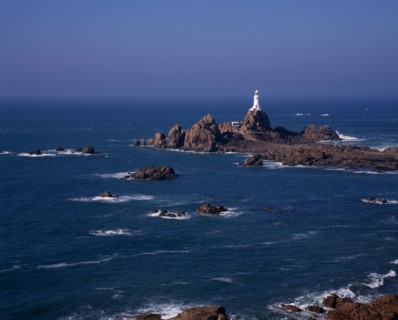 UNITED KINGDOM, Channel Islands, Jersey, St Brelade. Corbiere Lighthouse and rocky foreshore