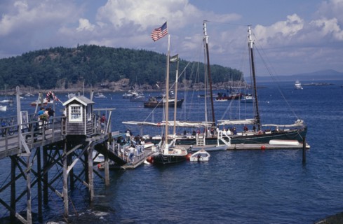 USA, Maine, Bar Harbour, "Wooden jetty with yacht moored at side, various boats on water and tree