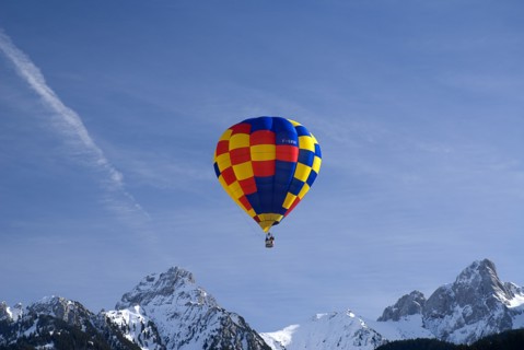 SWITZERLAND, Canton de Vaud, Chateau d'Oex, One Hot Air Balloon in flight above jagged snow covered