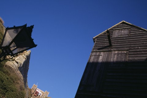 ENGLAND, East Sussex, Hastings, The Net Shops. Tall black wooden huts used for storing fishing nets