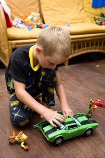 RELIGION, Festivals, Christmas, Young boy in his pyjamas playing on the floor with his green toy
