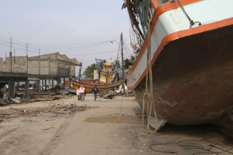 THAILAND, Phang Nga District, Nam Khem, "Tsunami. People walk past boats that have been pushed onto