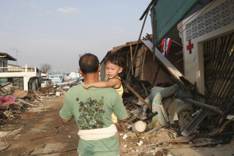 THAILAND, Phang Nga District, Nam Khem, Tsunami. One of the villagers with his child walks passed