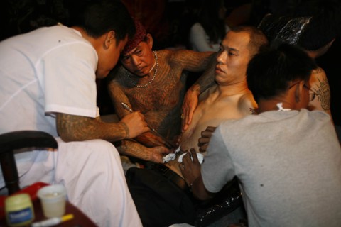 THAILAND, Phuket, Man having tattoo applied to torso.
