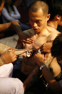 THAILAND, Phuket, Man having tattoo applied to torso.