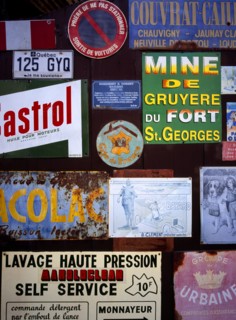 FRANCE, Indre et Loire, Chinon, A collection of enamelled advertising signs seen on a garage door.