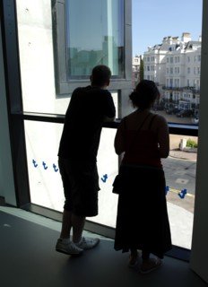 ENGLAND, East Sussex, Eastbourne, Young silhouetted couple looking out the window of the Towner