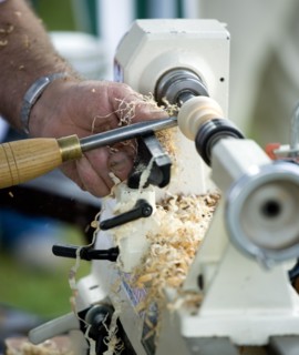 ENGLAND, West Sussex, Findon, Findon village Sheep Fair Man using a wood lathe with a chisel