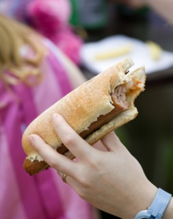 ENGLAND, West Sussex, Findon, Findon village Sheep Fair Teenage girl holding a hot dog with tomato