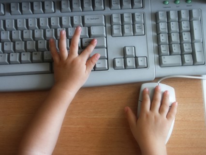 CHILDREN, Education, Computers, Cropped view of child using a computer showing hands on keyboard