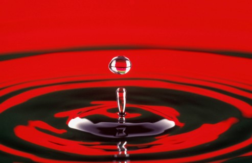 WATER, Droplet, Water drop at moment of suspension and circular ripple effect below.  Bright red