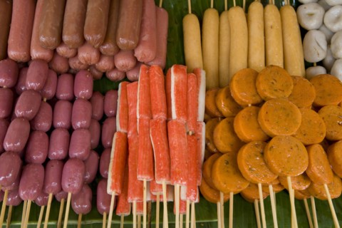 THAILAND, North, Chiang Mai, Close up of a selection of food on wooden skewers in the market.
