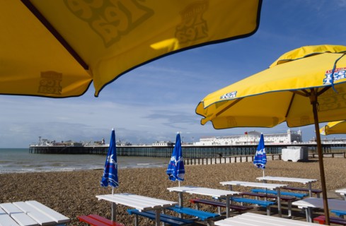 ENGLAND, East Sussex, Brighton, The Pier at low tide with shingle pebble beach in foreground seen