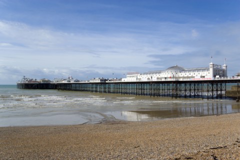 ENGLAND, East Sussex, Brighton, The Pier at low tide with shingle pebble beach in foreground.