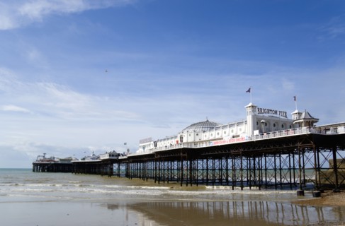 ENGLAND, East Sussex, Brighton, The Pier at low tide with shingle pebble beach in foreground.