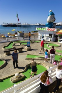 ENGLAND, East Sussex, Brighton, Adults and children playing miniature golf on a Crazy Golf course