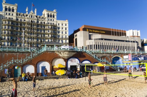 ENGLAND, East Sussex, Brighton, Young people playing beach volleyball on sand on the seafront with