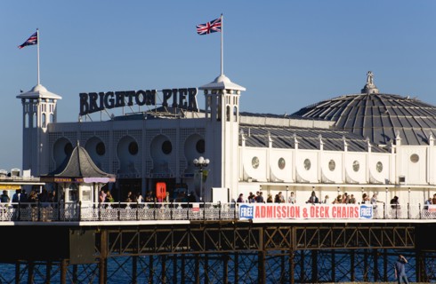 ENGLAND, East Sussex, Brighton, The Pier at low tide with people walking on the pier.