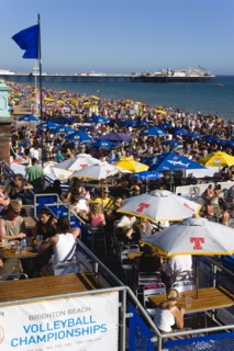 ENGLAND, East Sussex, Brighton, People sitting under sun shade umbrellas at tables on the promenade