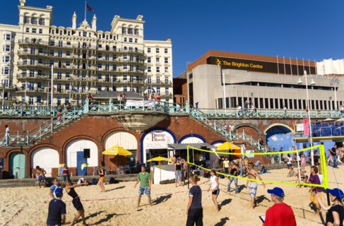 ENGLAND, East Sussex, Brighton, Young people playing beach volleyball on sand on the seafront with