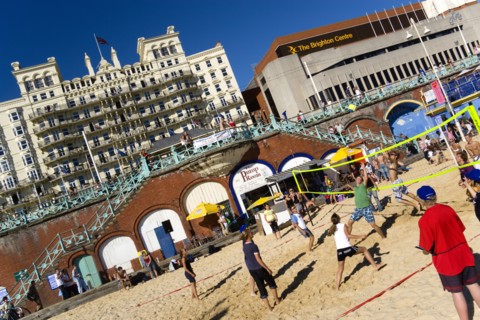 ENGLAND, East Sussex, Brighton, Young people playing beach volleyball on sand on the seafront with