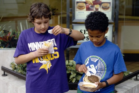 England, East Sussex, Brighton, Multicultural group of young boys adding salt to their takeaway