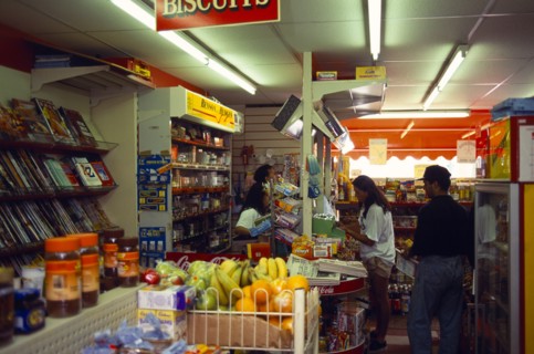 England, East Sussex, Brighton, Staff behind the counter of a corner grocery shop serving customers