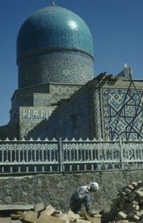 UZBEKISTAN, Samarkand, Bibi-Khanym Mosque exterior with construction worker in the foreground.