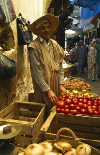 MOROCCO, Fez, Male stallholder behind crates of produce at the fruit market in the souk, pair of