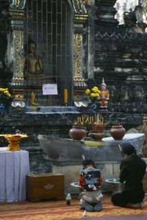 Thailand, North, Chiang Mai, Wat Chettawan Buddhist temple on Tha Phae Road with woman and young