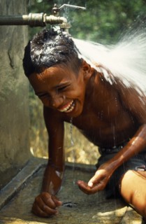 Dominican Republic, Laughing boy with head under water tap.