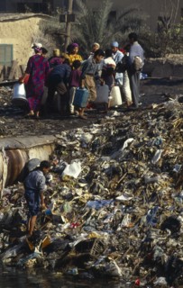 Egypt, Cairo, People standing beside rubbish tip in the Imbaba area of the city.