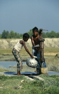 Bangladesh, Hatiya, Two boys drawing water from a UNICEF well into aluminium pitcher.