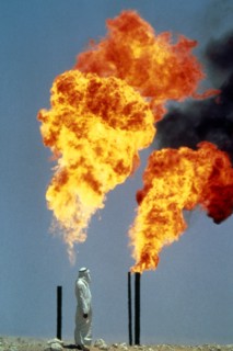 Saudi Arabia, Arab man standing next to gas burning off from oil well.