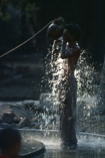 Myanmar, Myinkaba Village, Boy bathing outdoors in village near Pagan with sunlight catching the