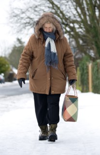England, West Sussex, Chichester, Middles aged woman in warm clothing carrying shopping bag and