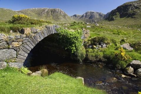 IRELAND, County Donegal, The Poisoned Glen, A stream runs under an old style stone bridge with the