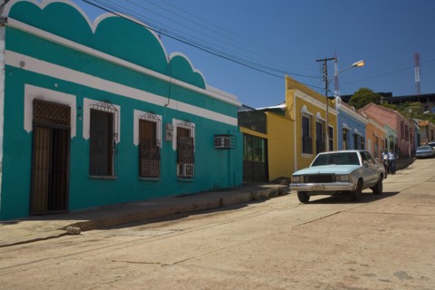 VENEZUELA, Bolivar State, Ciudad Bolivar, Colorful, candy like, buildings and an old American car